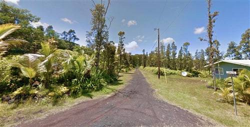 Aerial view of a 0.18-acre lot in Nanawale Estates near Hilo, Hawaii, showing land with nearby Lanai Road and surrounding greenery.
