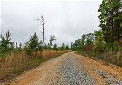 Scenic view of Tennessee Benton County Red Barn Ranch lot 32 with a red barn and stream on the 7.52-acre property.