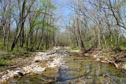 Aerial view of Cedar Ridge Ranch in Phelps County, Missouri, featuring 5.87 acres with a creek and lush landscape.