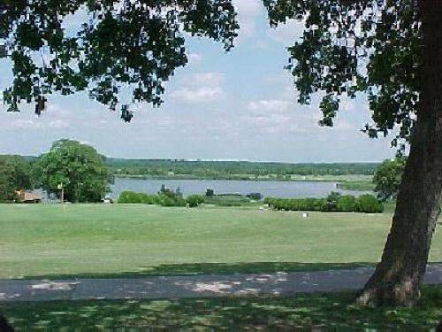 Aerial view of a .23-acre land parcel in Falconhead Resort, Love County, Oklahoma, showcasing open land with trees and surrounding properties.