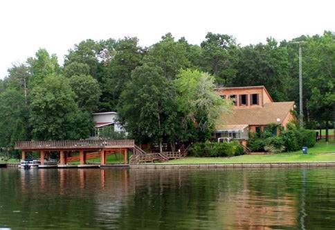 A scenic view of Cypress Springs Lake in Franklin County, Texas, showing calm water and surrounding trees on a .11-acre property.
