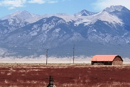 Aerial view of Colorado Alamosa County 160-acre property in San Luis Valley, featuring open land and surrounding natural landscape.