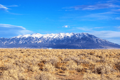 A scenic view of Colorado's Alamosa County Wild Horse Ranch with open land and distant mountains, showing the rural property landscape.