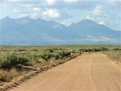 Aerial view of Colorado San Luis Valley ranch land in Costilla County, featuring open grassy 5-acre lot with surrounding natural landscape.