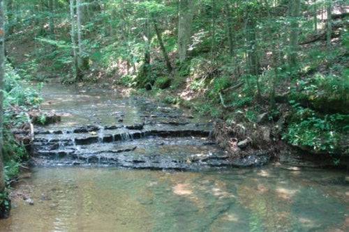 Aerial view of Sugartree Falls creek and waterfall on 15.47-acre land in Wayne County, Tennessee, offered by Onlinelandsales.